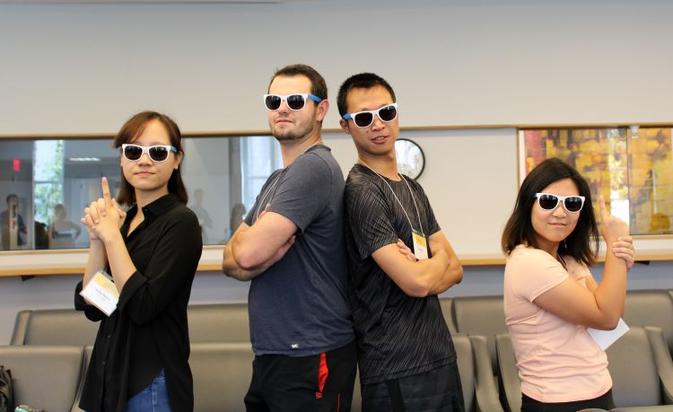 four students pose "Charlie's Angels" style wearing matching sunglasses